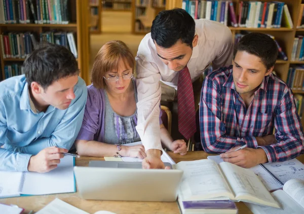 Estudiantes maduros con profesor y portátil en la biblioteca — Foto de Stock