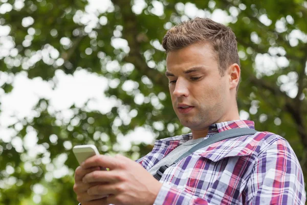 Knappe bezorgd student permanent en texting — Stockfoto