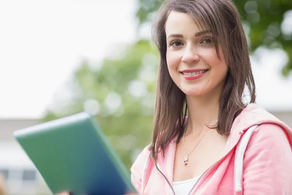 Улыбающаяся молодая студентка, пользующаяся планшетным ПК на улице — стоковое фото