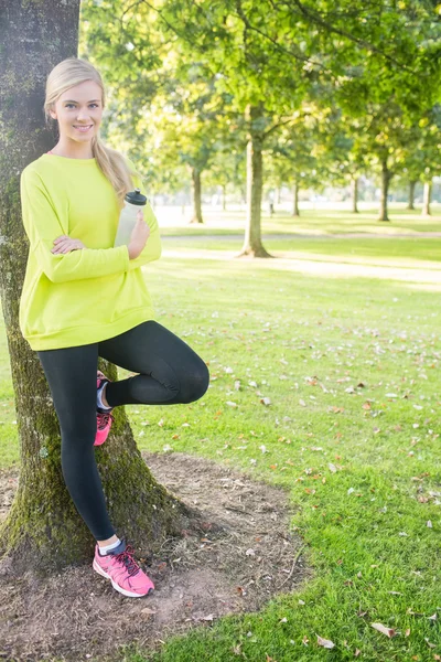 Fit cheerful blonde holding sports bottle — Stock Photo, Image