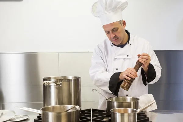 Jefe de cocina enfocado usando molino de pimienta —  Fotos de Stock