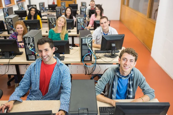 Estudiantes sonrientes en la sala de computadoras de la universidad — Foto de Stock
