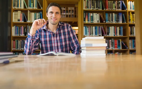Uśmiechający się dojrzały student studia na biurko w bibliotece — Zdjęcie stockowe