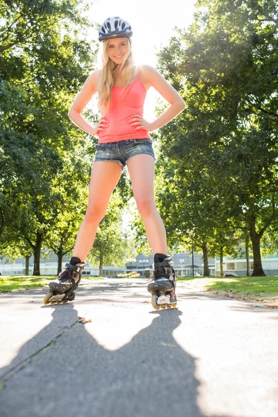Случайно улыбающаяся блондинка, стоящая на руках на бедрах в роликах — стоковое фото