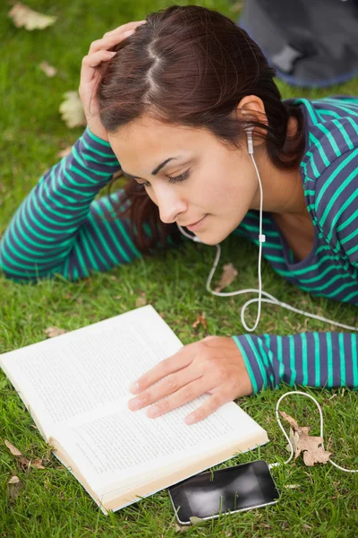 Lugn avslappnad student liggande på gräs läser en bok — Stockfoto