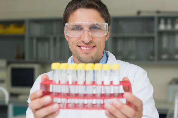 Investigador masculino sonriente con tubos de ensayo en el laboratorio — Foto de Stock