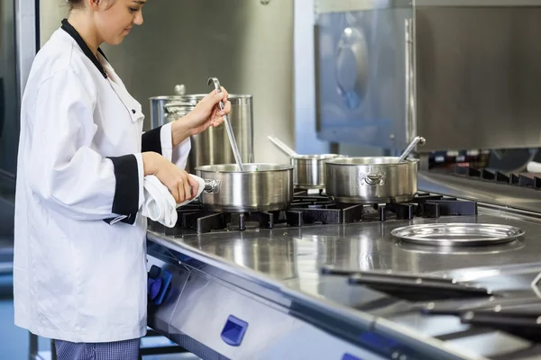 Jonge chef-kok roeren met pollepel — Stockfoto