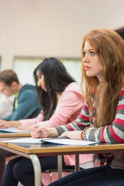 Jovens estudantes escrevendo notas em sala de aula — Fotografia de Stock