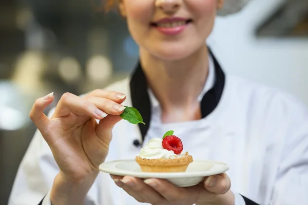 Cocinero jefe feliz poniendo hoja de menta en poco pastel en el plato —  Fotos de Stock