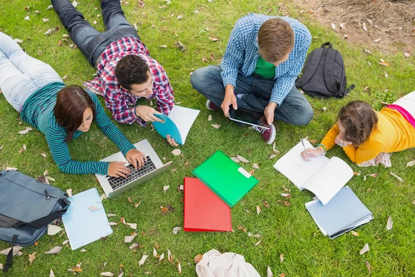 Estudiantes universitarios usando laptop mientras hacen la tarea en el parque — Foto de Stock