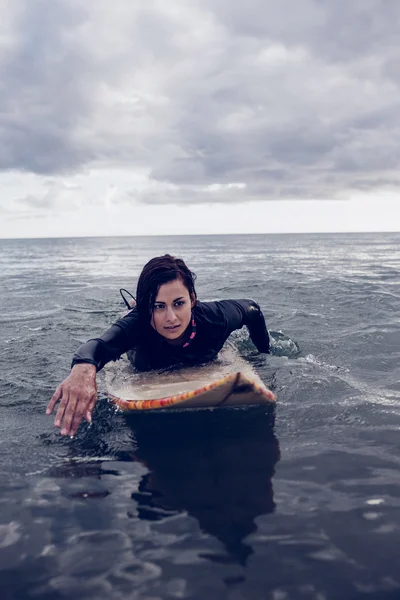 Donna che nuota sopra la tavola da surf in acqua — Foto Stock