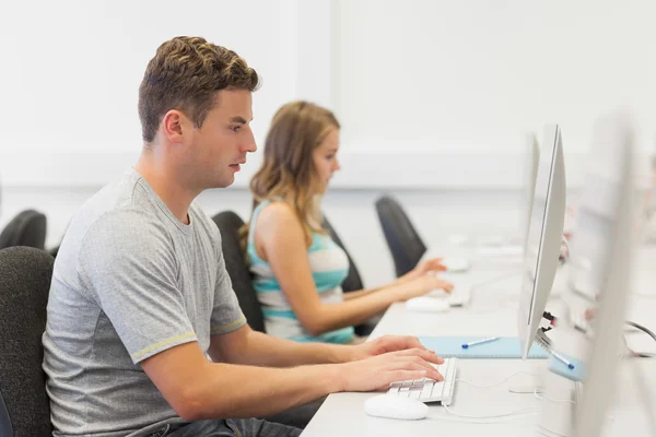 Dois estudantes sérios trabalhando no computador individualmente — Fotografia de Stock