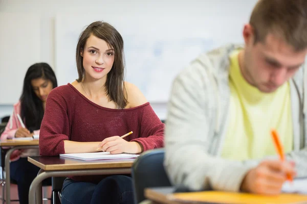 Studente donna con gli altri a scrivere appunti in classe — Foto Stock