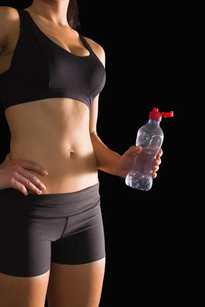 Mid section of slim woman in sportswear holding a water bottle — Stock Photo, Image