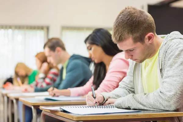 Jovens estudantes escrevendo notas em sala de aula — Fotografia de Stock