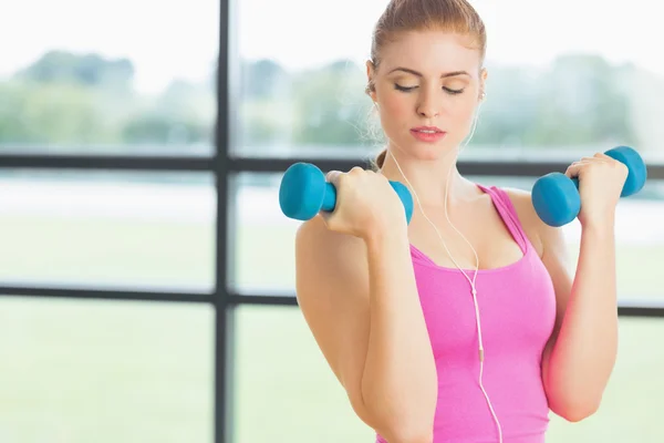 Fit woman exercising with dumbbells in fitness studio — Stock Photo, Image