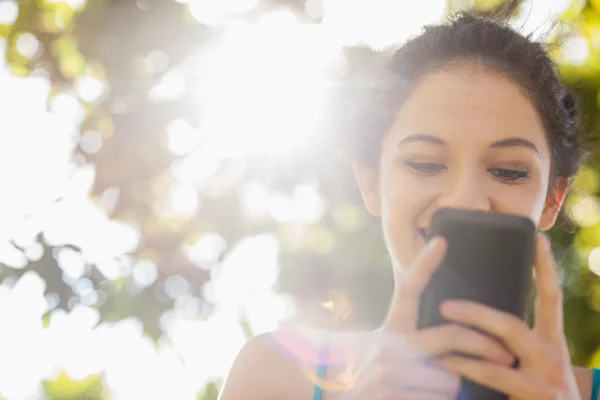 Šťastný bruneta žena textilie s její smartphone — Stock fotografie