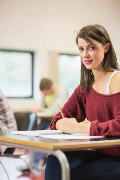 Studentessa con altri che scrivono appunti in classe — Foto Stock