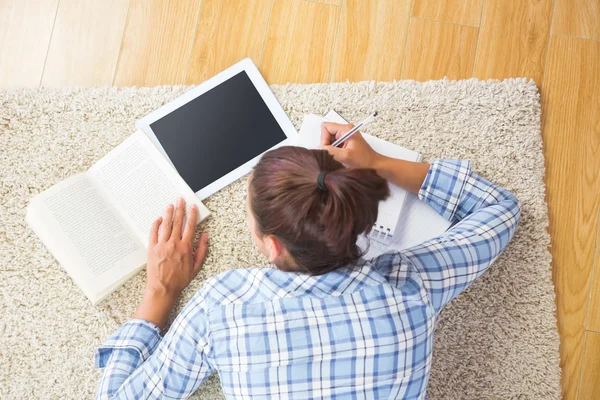 Brünette Studentin liegt auf dem Boden und erledigt Aufgaben — Stockfoto