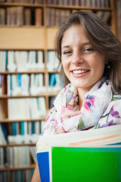 図書館の本棚に対する女子学生の笑みを浮かべてください。 — ストック写真