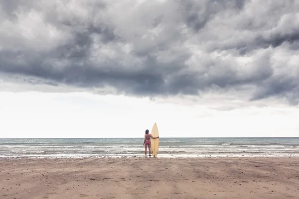 Mujer tranquila en bikini con tabla de surf en la playa —  Fotos de Stock