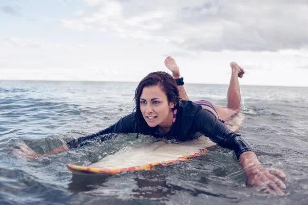 Giovane donna che nuota sopra la tavola da surf in acqua — Foto Stock