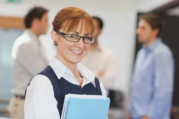 Portrait of female mature student posing in classroom holding so — Stock Photo, Image