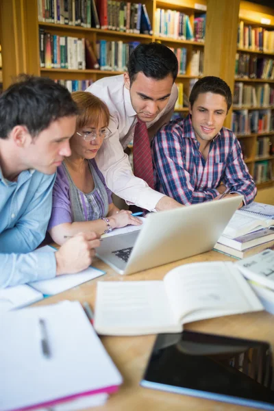 Mature students with teacher and laptop in library — Stock Photo, Image