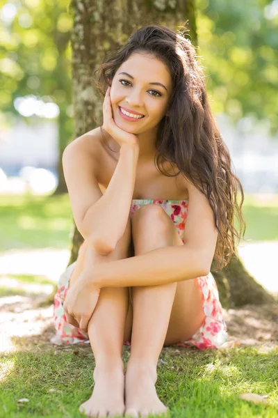 Stylowy szczęśliwy brunetka siedzący pod drzewem — Zdjęcie stockowe