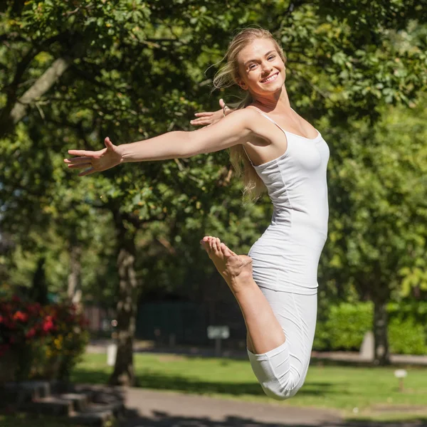 Seitenansicht einer jungen, fitten Frau, die mit ausgebreiteten Armen springt — Stockfoto