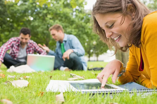 学生使用 tablet pc，而男性使用笔记本电脑在公园里 — 图库照片