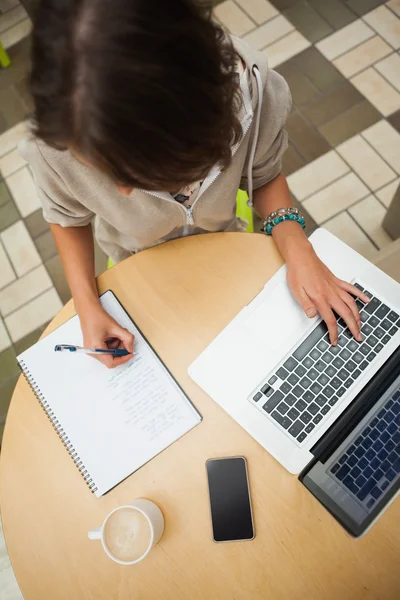 Student huiswerk door laptop aan cafetaria tafel — Stockfoto