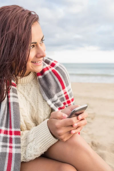 Žena v deka s mobil na pláži — Stock fotografie
