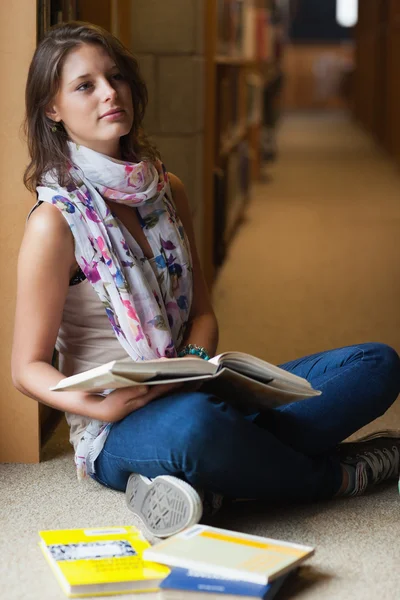 Doordachte student zitten met boeken in de bibliotheek — Stockfoto