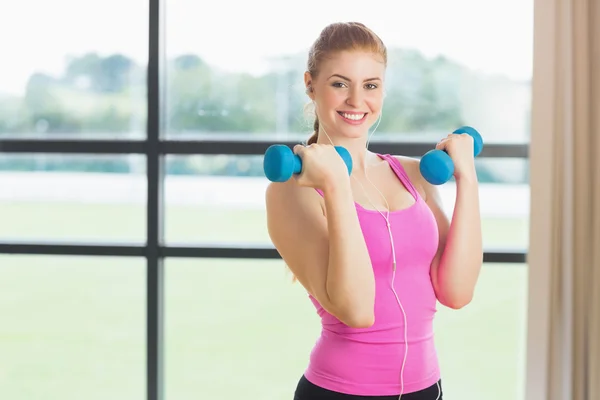 Fit woman exercising with dumbbells in fitness studio — Stock Photo, Image