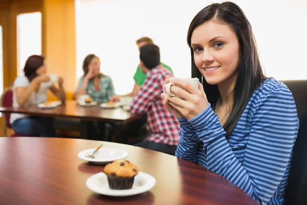 Улыбающаяся женщина пьет кофе и кексы в кафе — стоковое фото