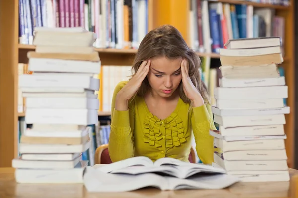 Frustrerad söt student som studerar mellan högar av böcker — Stockfoto