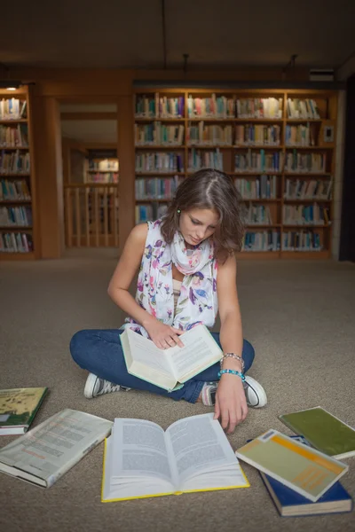 Studentin sitzt mit Büchern auf dem Bibliotheksboden — Stockfoto