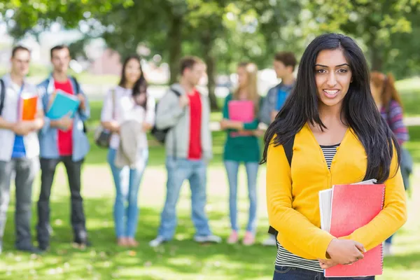 Dziewczynka gospodarstwa książki z niewyraźne studentów w parku — Zdjęcie stockowe