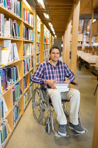 Man in wheelchair by bookshelf in the library — Stock Photo, Image