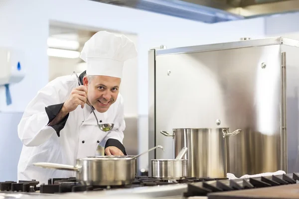 Chef-kok proeverij levensmiddelen uit pollepel glimlachen — Stockfoto