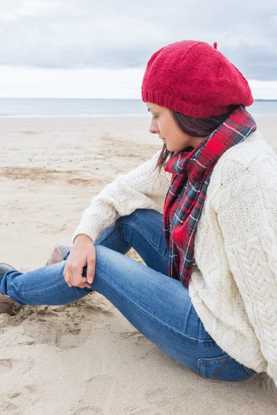 ビーチで座っているスタイリッシュな暖かい服の女 — ストック写真