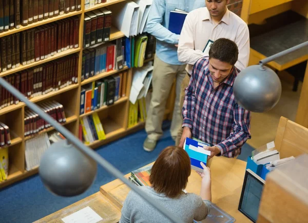Mogna studenter vid disken i college library — Stockfoto