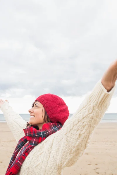 Frau in warmer Kleidung streckt ihre Arme am Strand aus — Stockfoto