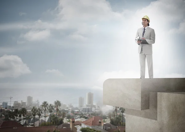 Architect with hard hat and clipboard against the sky and citysc