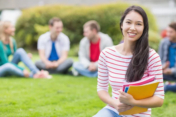 Sorridente studente universitario con gli amici offuscati nel parco — Foto Stock