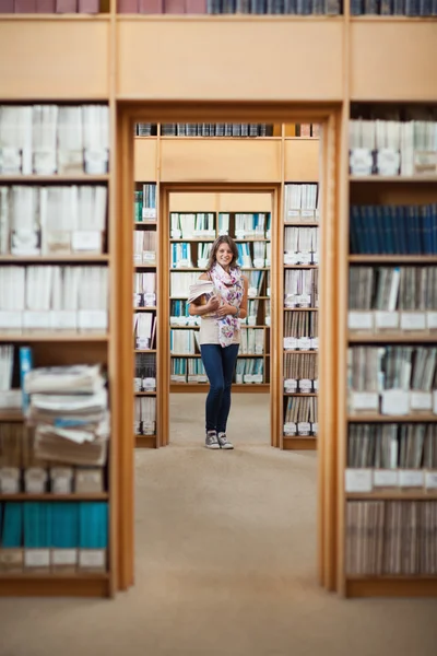 Comprimento total de uma estudante em pé na biblioteca — Fotografia de Stock