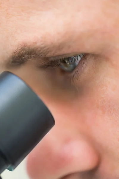Extreme close-up of a scientific researcher using microscope — Stock Photo, Image