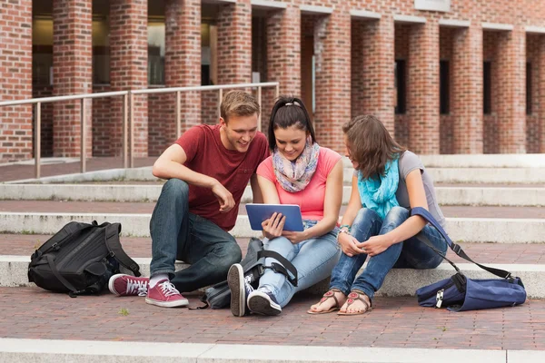 Smiling students sitting on stairs using tablet Royalty Free Stock Photos