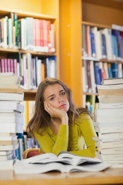 Tired beautiful student studying between piles of books — Stock Image Tired beautiful student studying between piles of books Stock Image